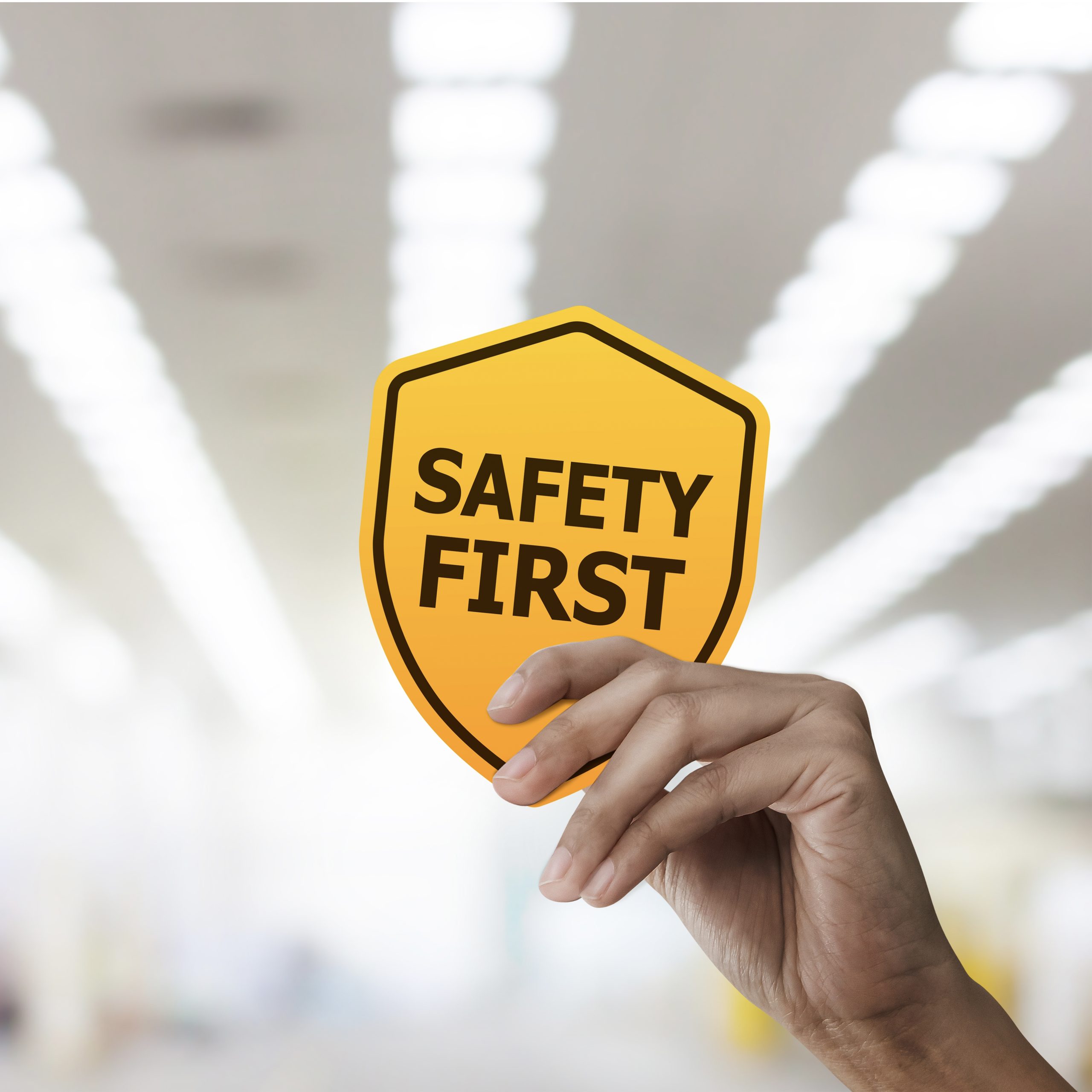 A hand holding a safety first sign
